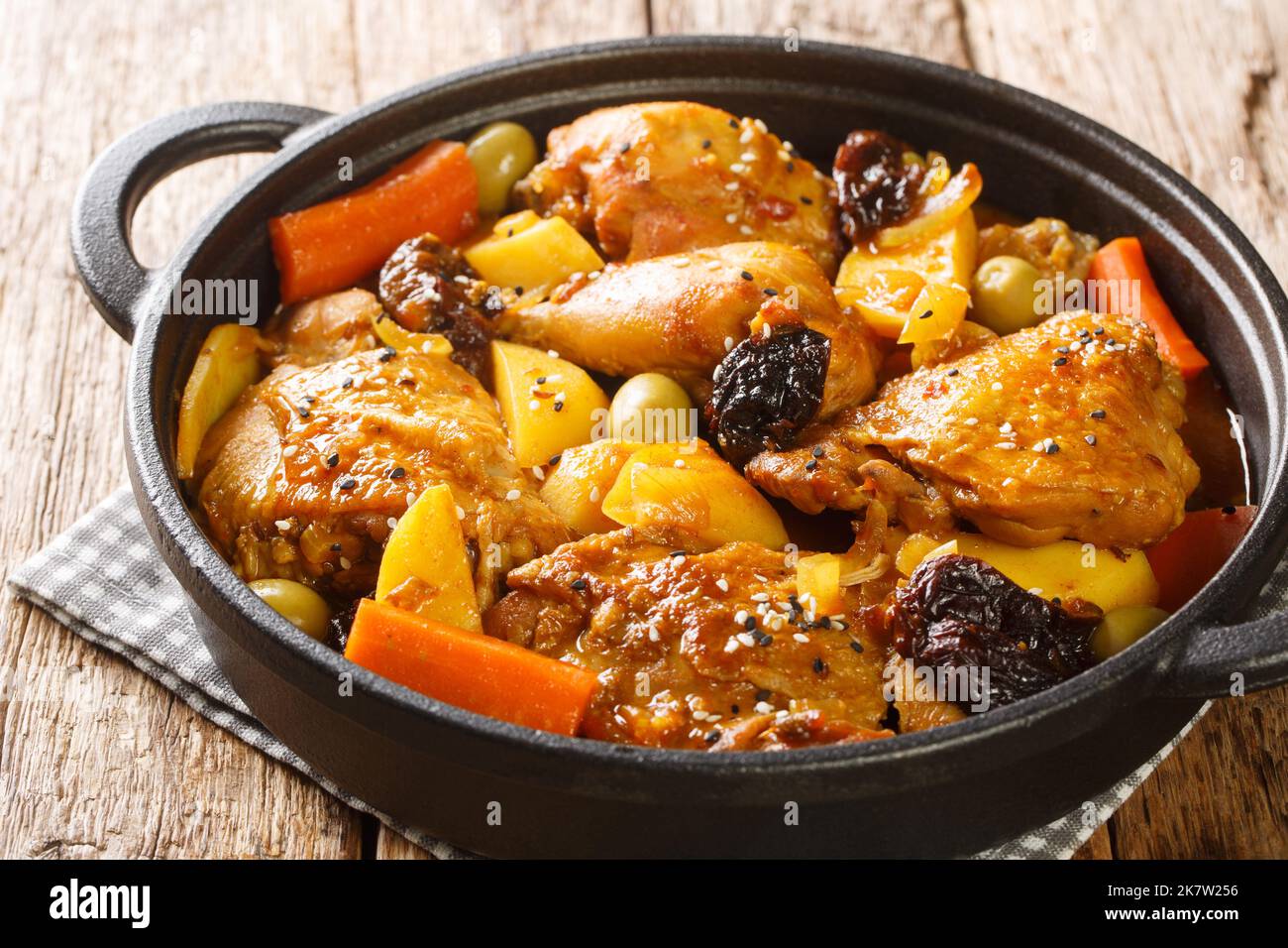 Gallo en chicha stew with chicken, prunes, vegetables, and spices cooked to have a wonderful flavor and aroma closeup on the pan on the wooden table. Stock Photo