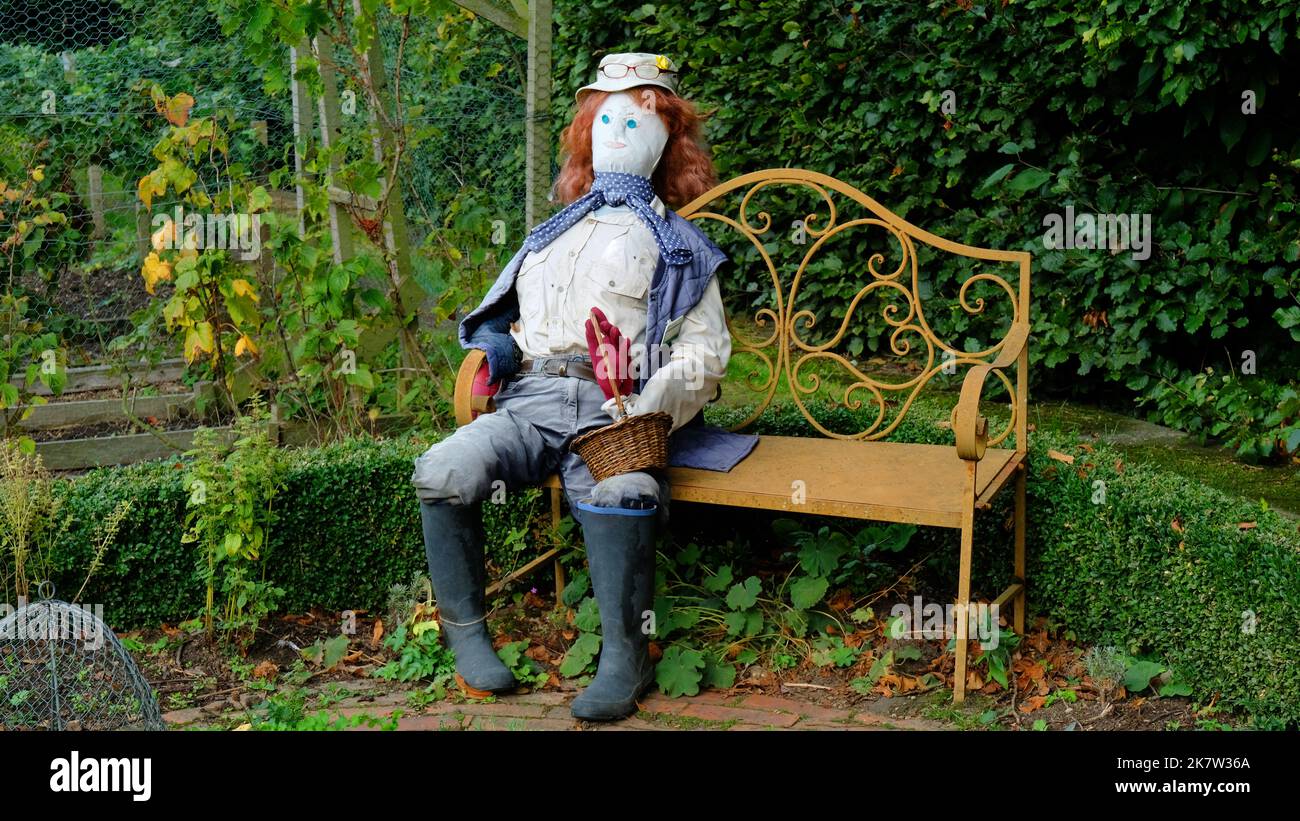 Scarecrow sitting on a seat in an English country garden - John Gollop ...