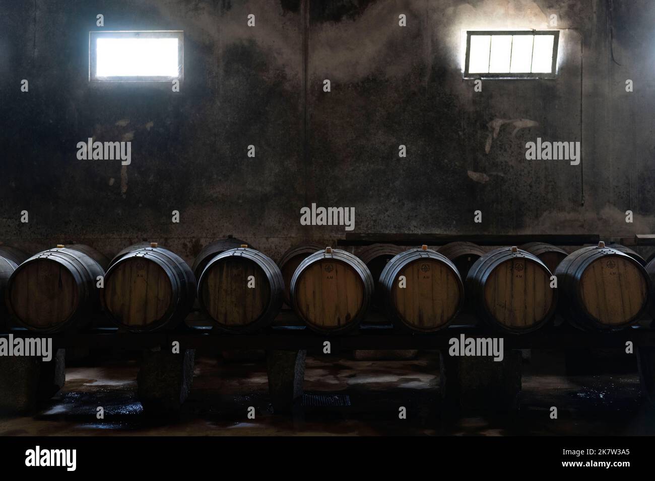 Wine aging in wooden barrels on a dark wine cellar Stock Photo