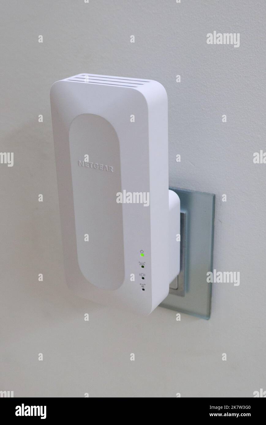 Netgear WiFi 6 mesh extender plugged into a wall socket at home Stock
