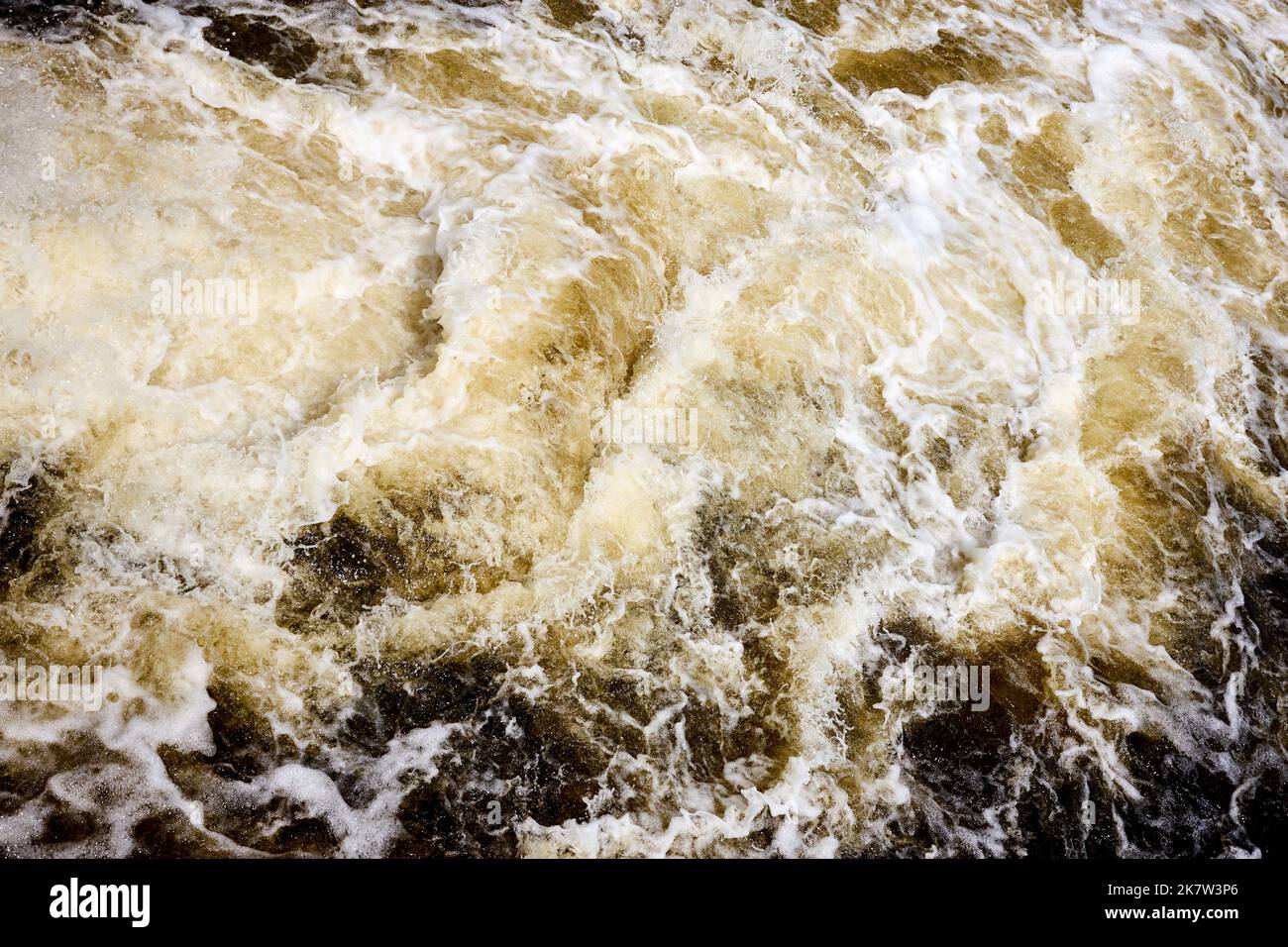 Wake brown water bubbling behind ship with bubbles and splashes background texture. Stock Photo