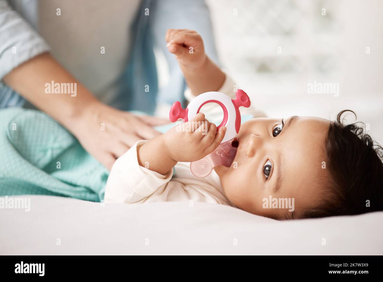 Her teether is the only thing that keeps her calm. an adorable little girl playing with a teething toy. Stock Photo