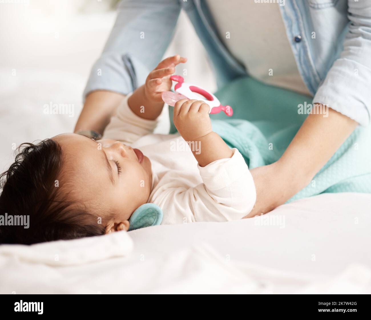 Getting her ready for the day. an adorable little girl playing with a teething toy. Stock Photo