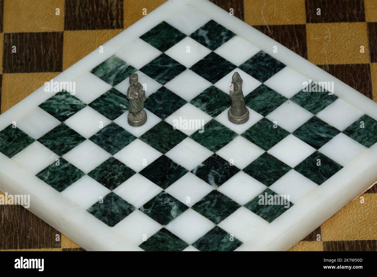 King and Queen chess pieces on a black and white marble chess board looking at each other. A Symbolic Couple. metal chess pieces. Stock Photo