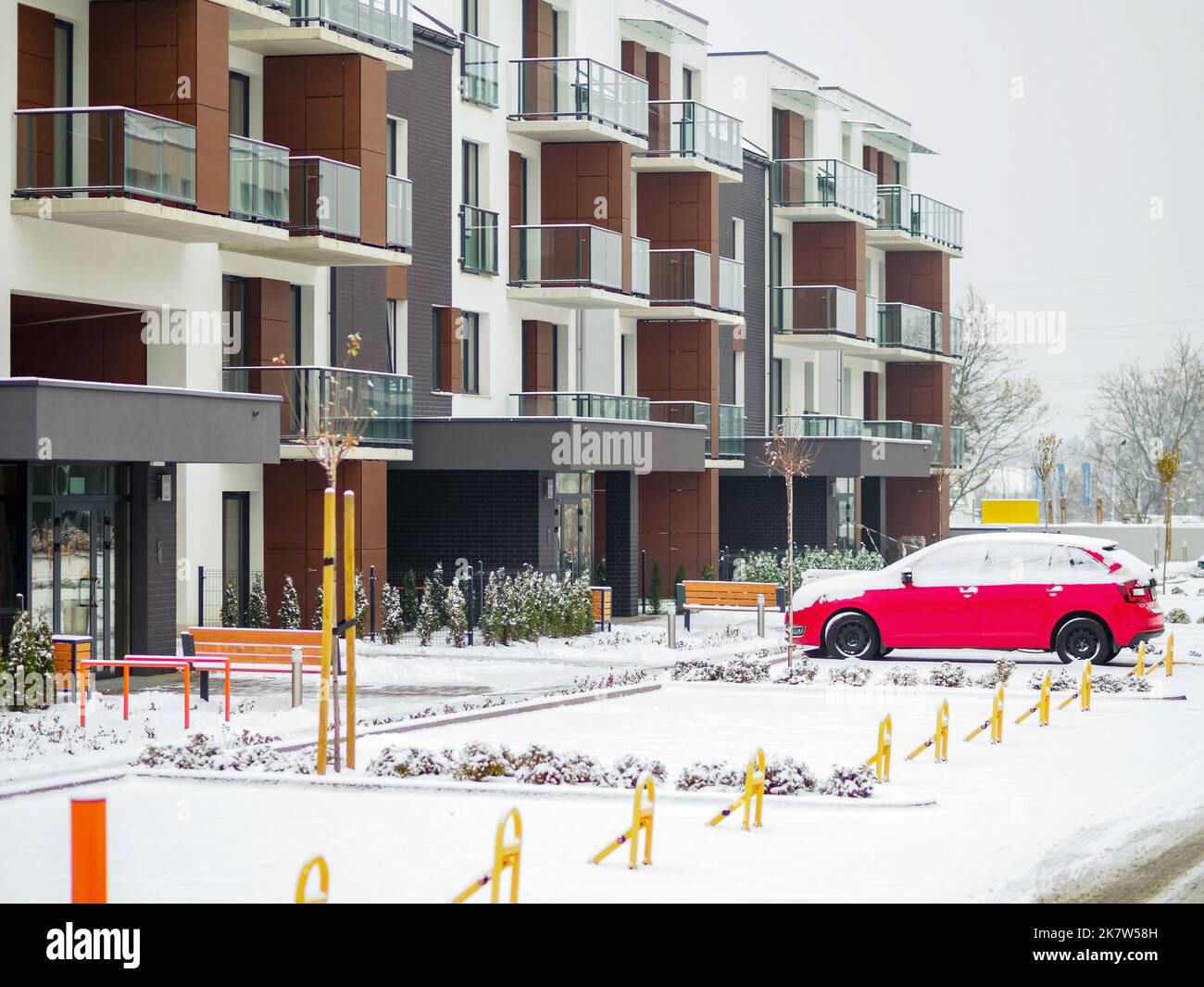 entrance to a modern apartment house and parked red car in a winter day Stock Photo