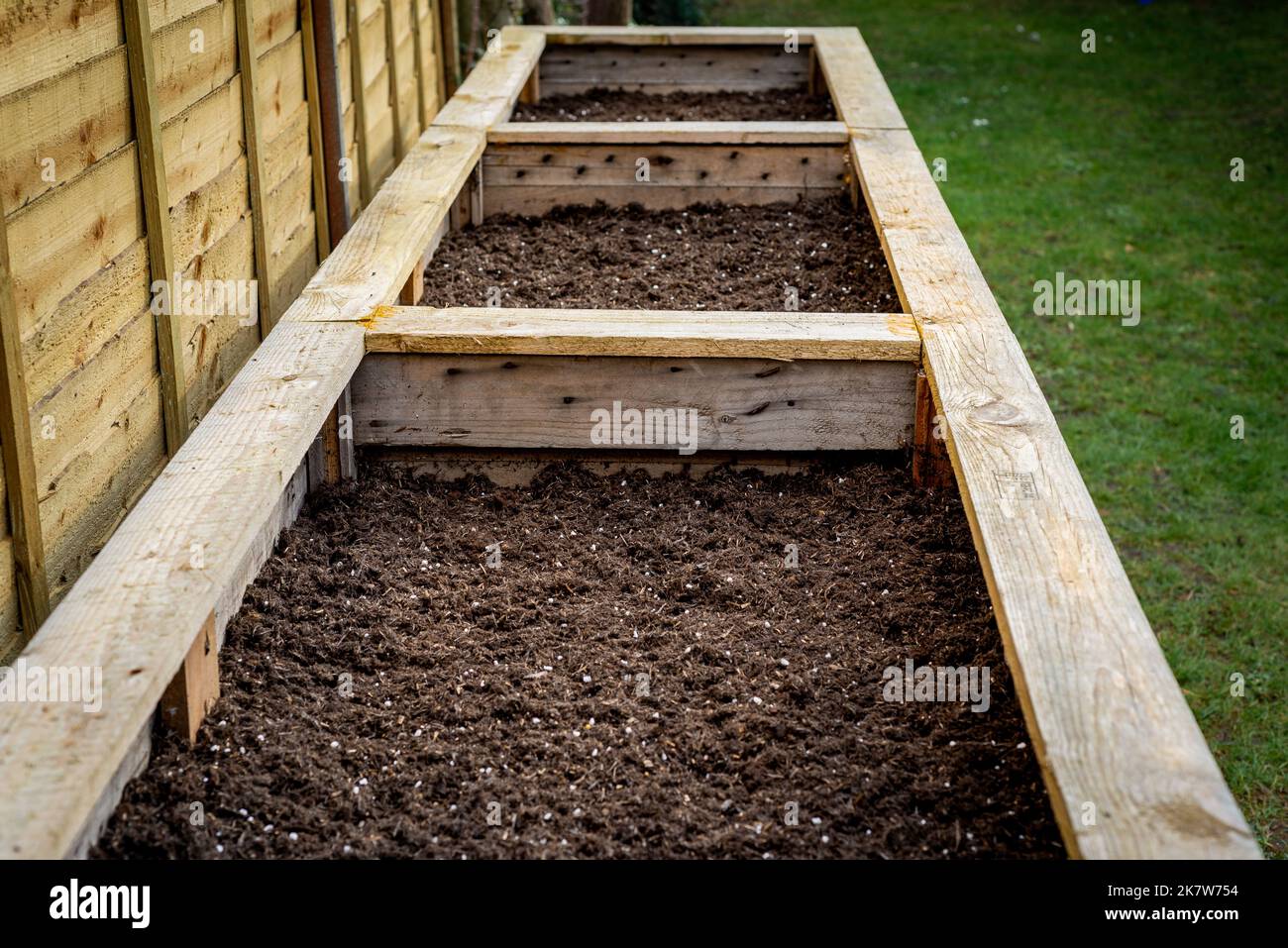 Close up of large wooden planter vegetable box containers in backyard