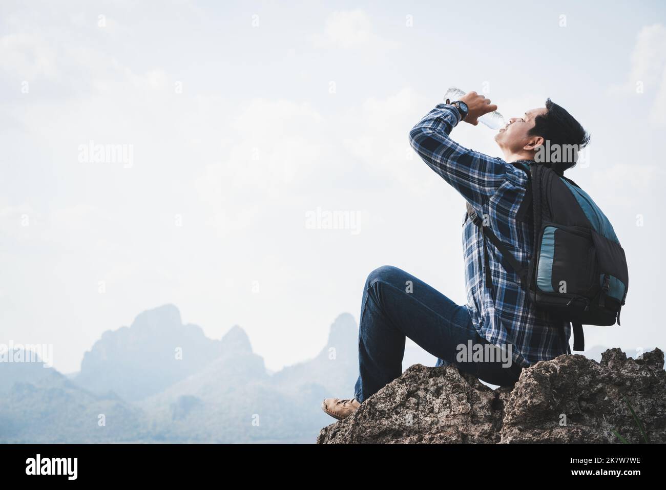 Success man hiker drink water at cliff edge on mountain top. Concept of