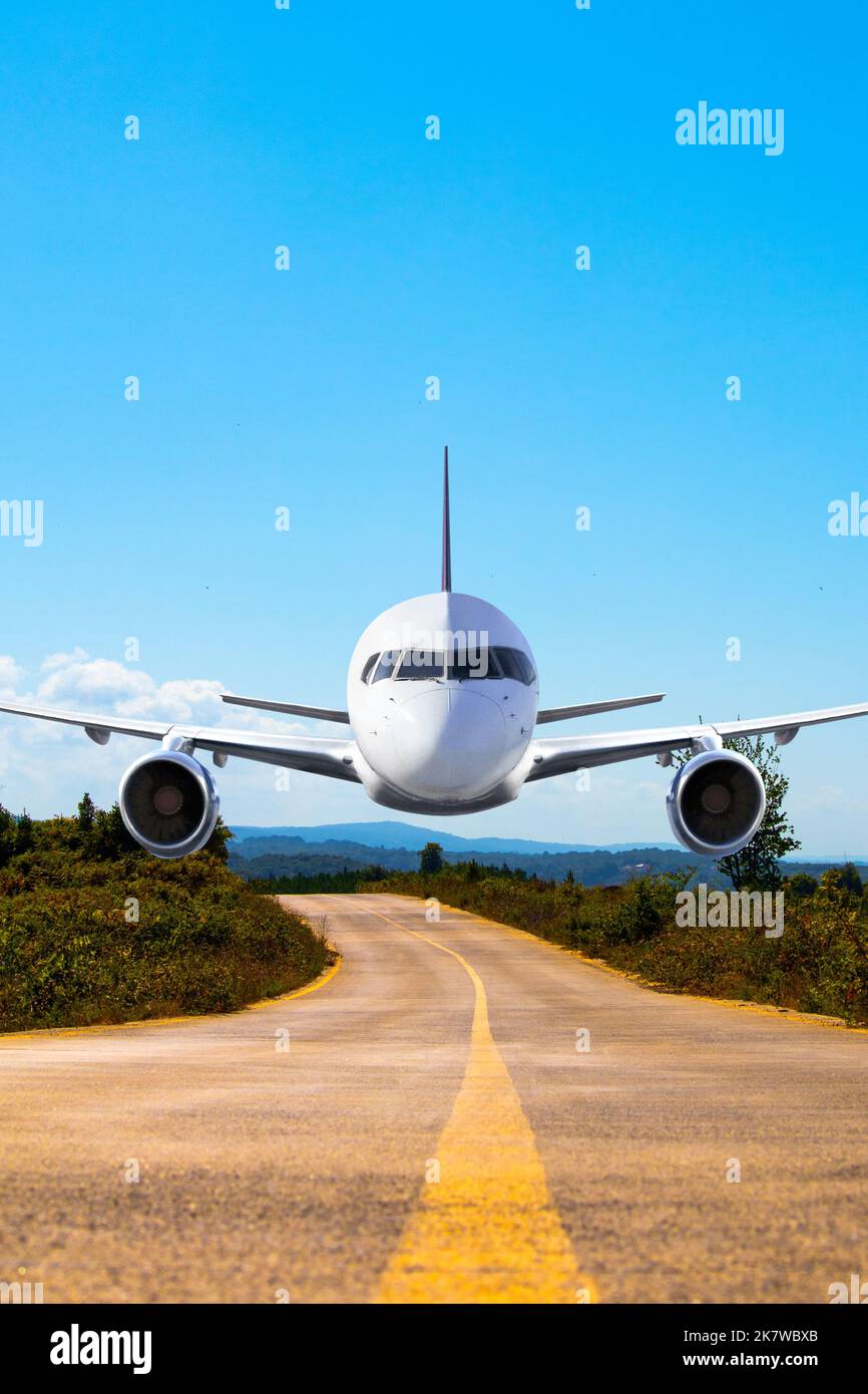 Airplane over the road, airplane making emergency landing on road between countryside. Aviation idea concept. Vertical photo. No people, nobody. Stock Photo
