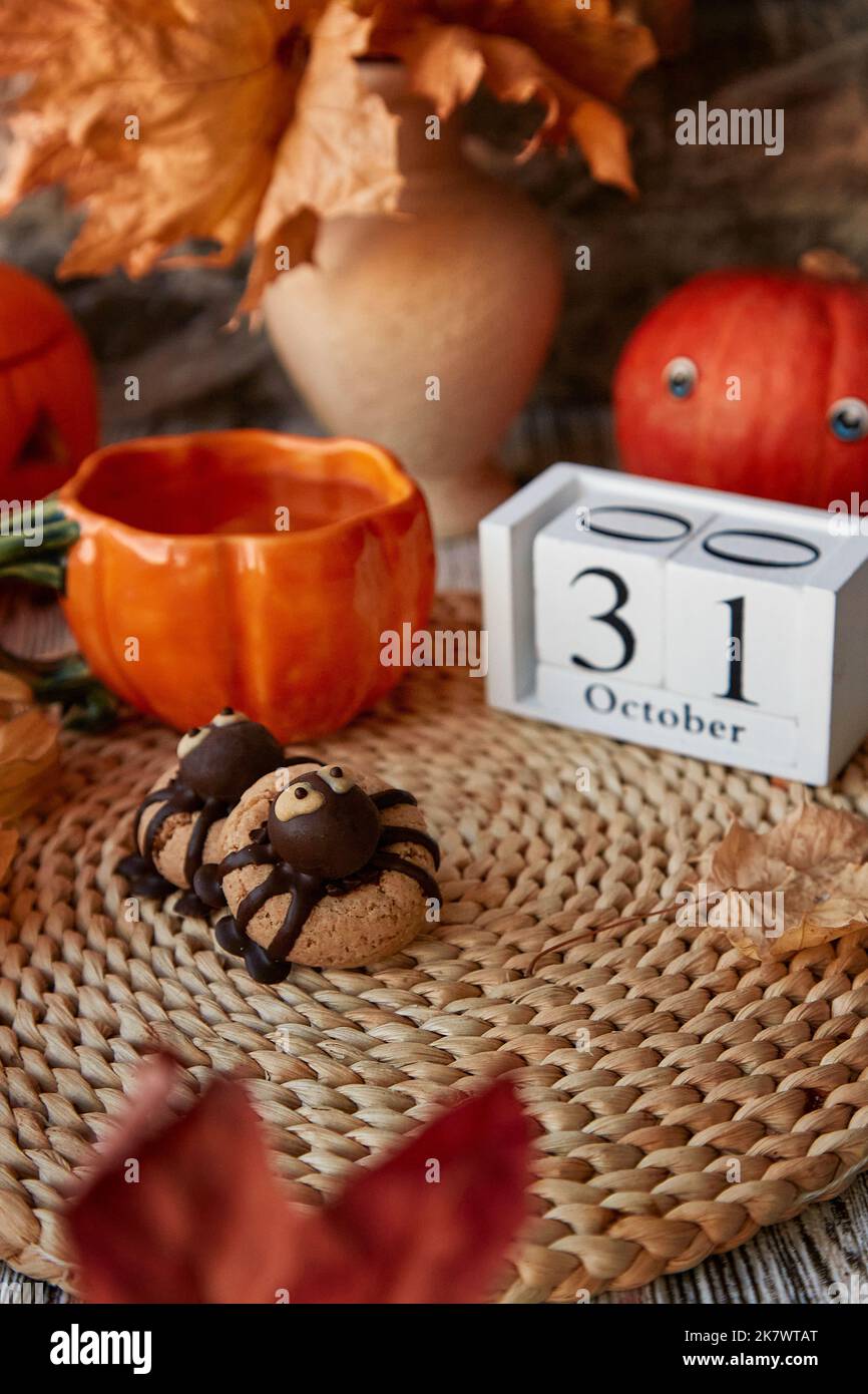 Autumnm aesthetics Halloween cookies in shape of spider and cup of tea in shape of pumpkin near 31 of October on calendar Stock Photo
