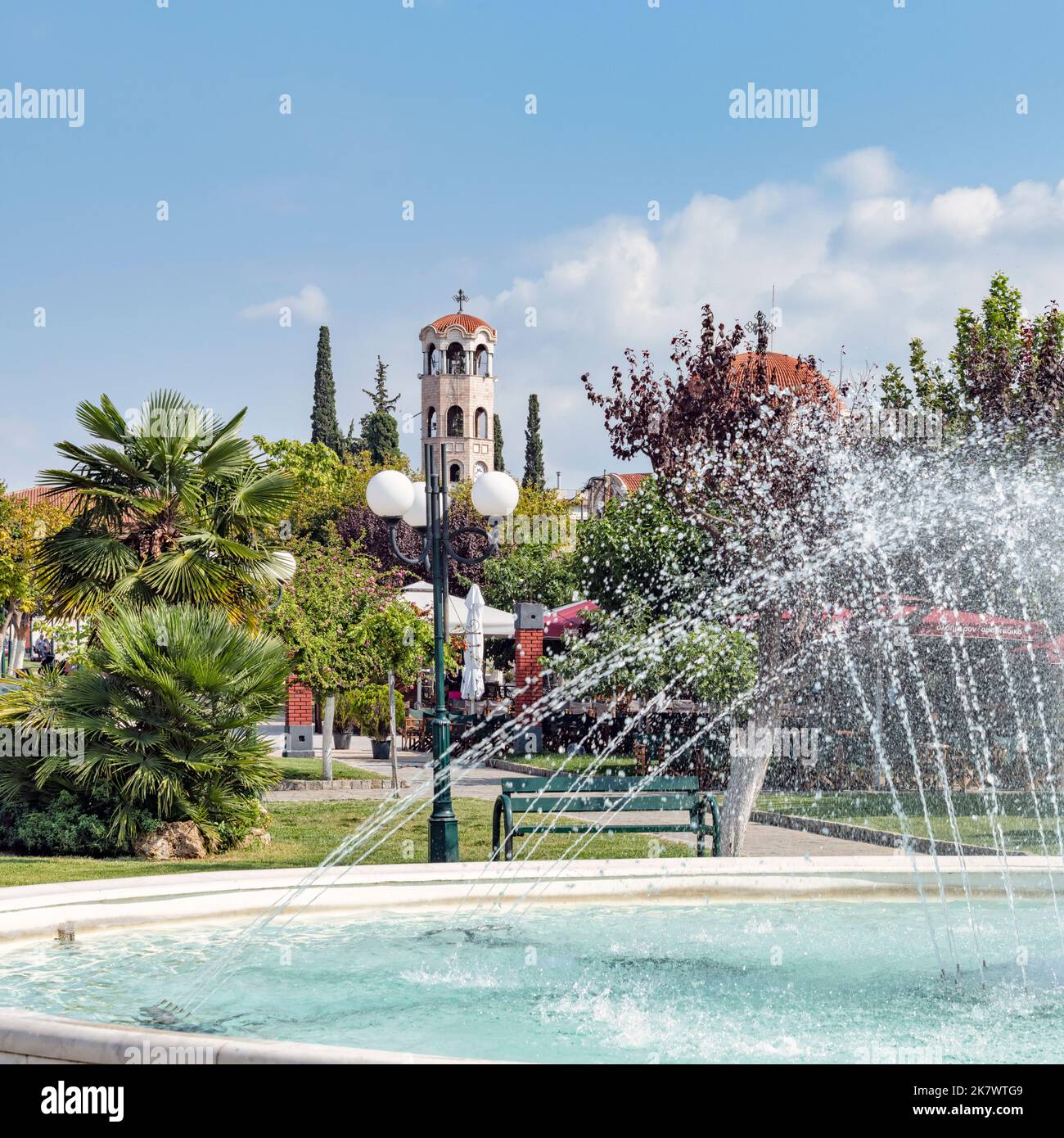 Springbrunnen im Park von Agios Athanasios in Griechenland mit Kirchturm im Hintergrund Stock Photo