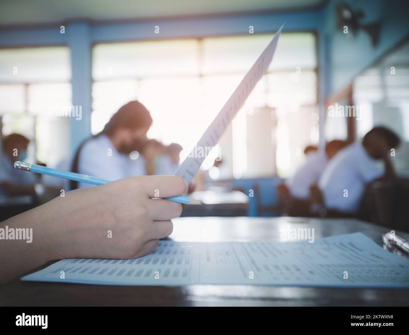 Close up hand of student reading and writing exam answer sheets