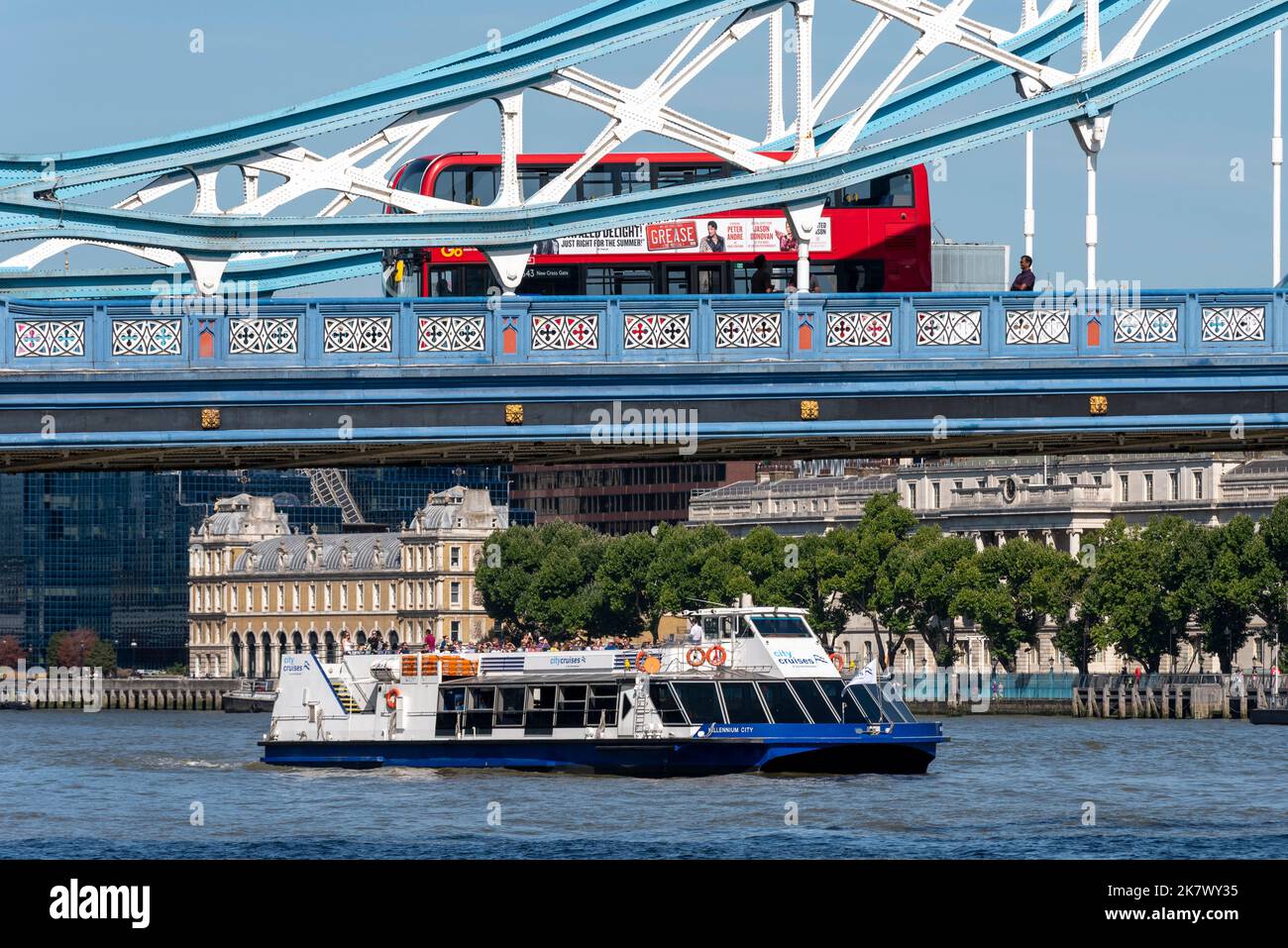 Transport in City of London, with red bus passing over Tower Bridge and City Cruises sailing under. Modes of transport in the city Stock Photo