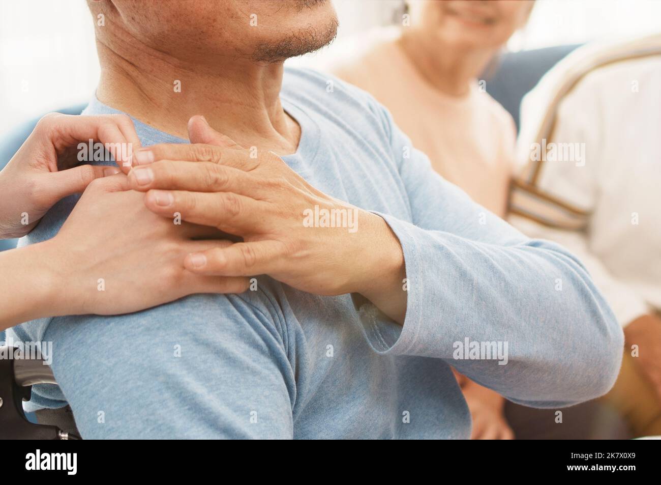 Mature man in elderly care facility gets help from hospital personnel nurse. Senior man, aged wrinkled skin hands and caregiver supportive hand close Stock Photo