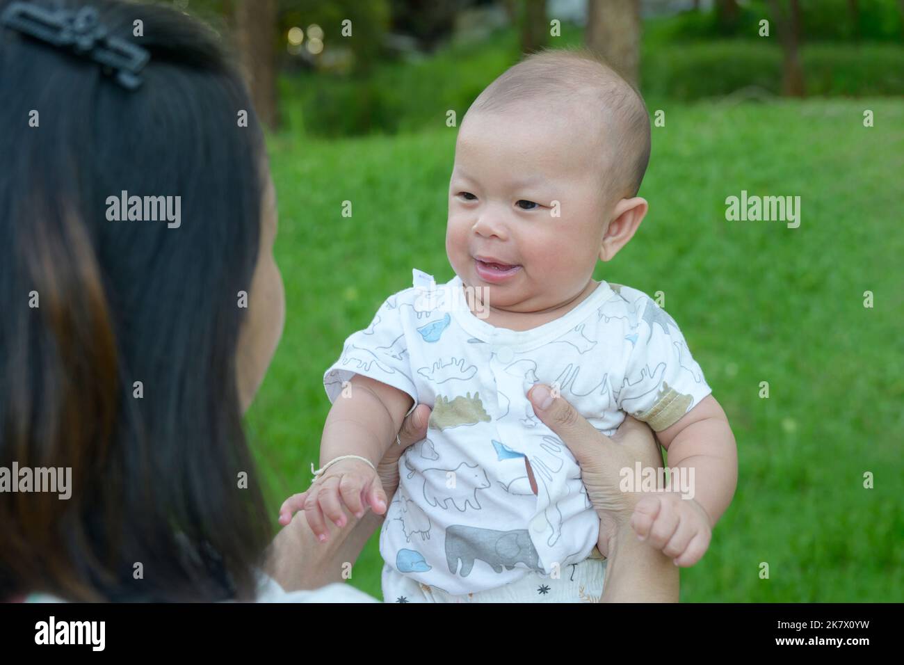 little baby girl smile in home garden kid look at the mother, mother hand carrying child in the morning. love, relationship concept Stock Photo