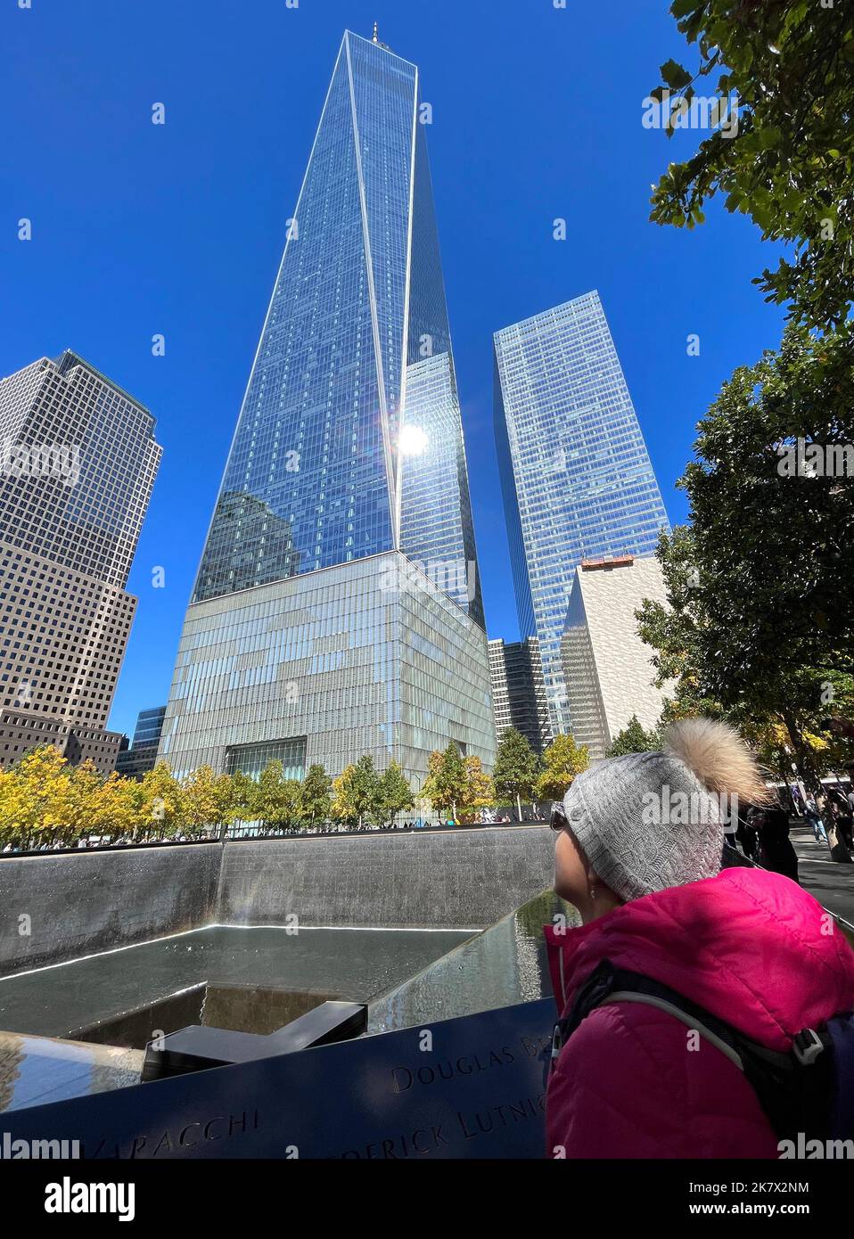 Teenager girl tourist admiring the Freedom Tower and fountain. Freedom Tower and Memorial Fountain commemorating the September 11 attacks of 2001, loc Stock Photo