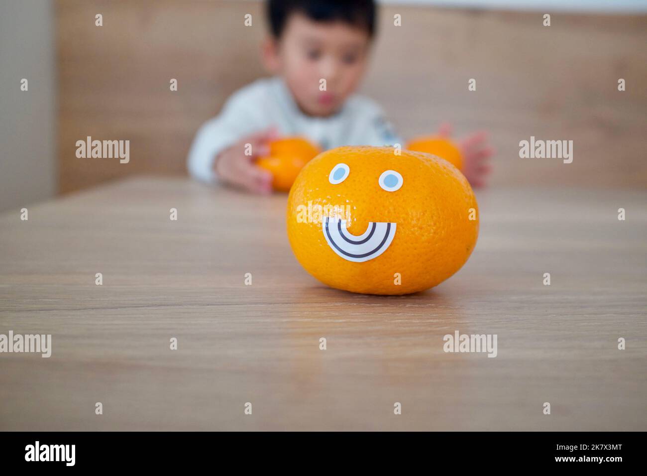 A mandarine with facial expressions. There was a little boy behind it. Stock Photo