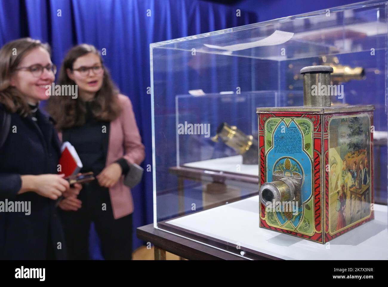 Potsdam, Germany. 19th Oct, 2022. Curator Henrike Okrent (r) explains a magic lantern in a cookie jar to a journalist at the Filmmuseum during the press conference for the exhibition 'Ich sehe was, was Du nicht siehst'. The experimental filmmaker and director Werner Nekes had collected about 25000 objects of cinematic art since the 1960s. Fourteen of them will be exhibited at the Potsdam Film Museum from October 21, 2022 to April 16, 2023. Credit: Soeren Stache/dpa/Alamy Live News Stock Photo