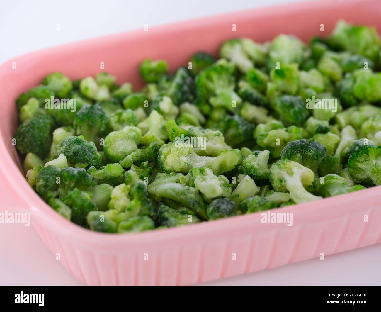 Frozen mini broccoli in a pink baking tray. Close up. Stock Photo