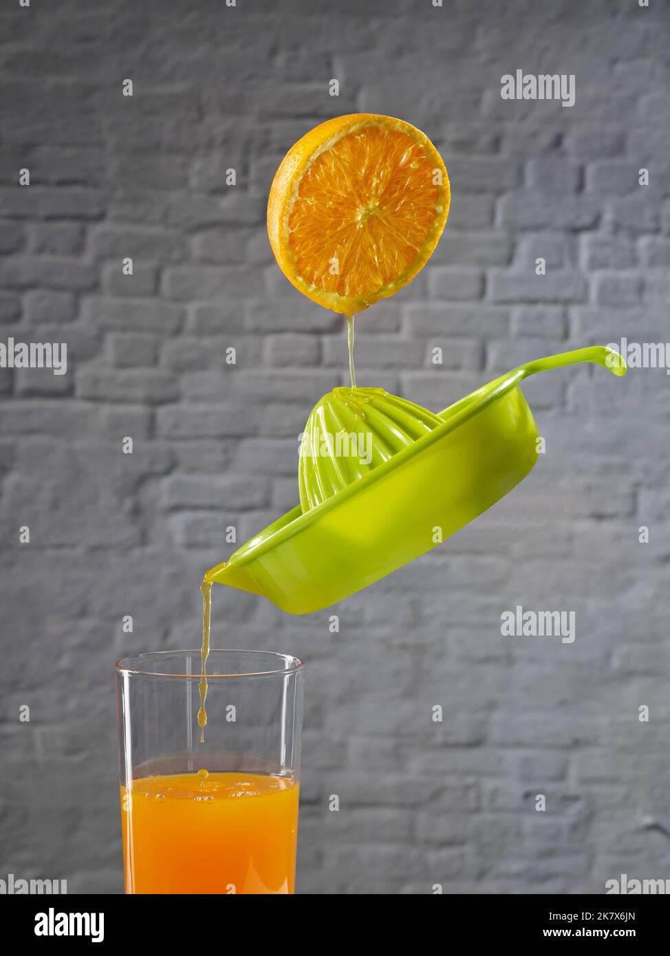 Juice falling from half an orange into a juicer, which is filling a