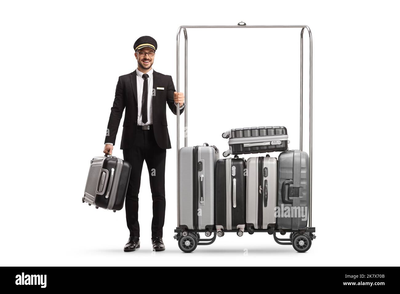 Bellboy with a suitcases standing next to a luggage cart isolated on