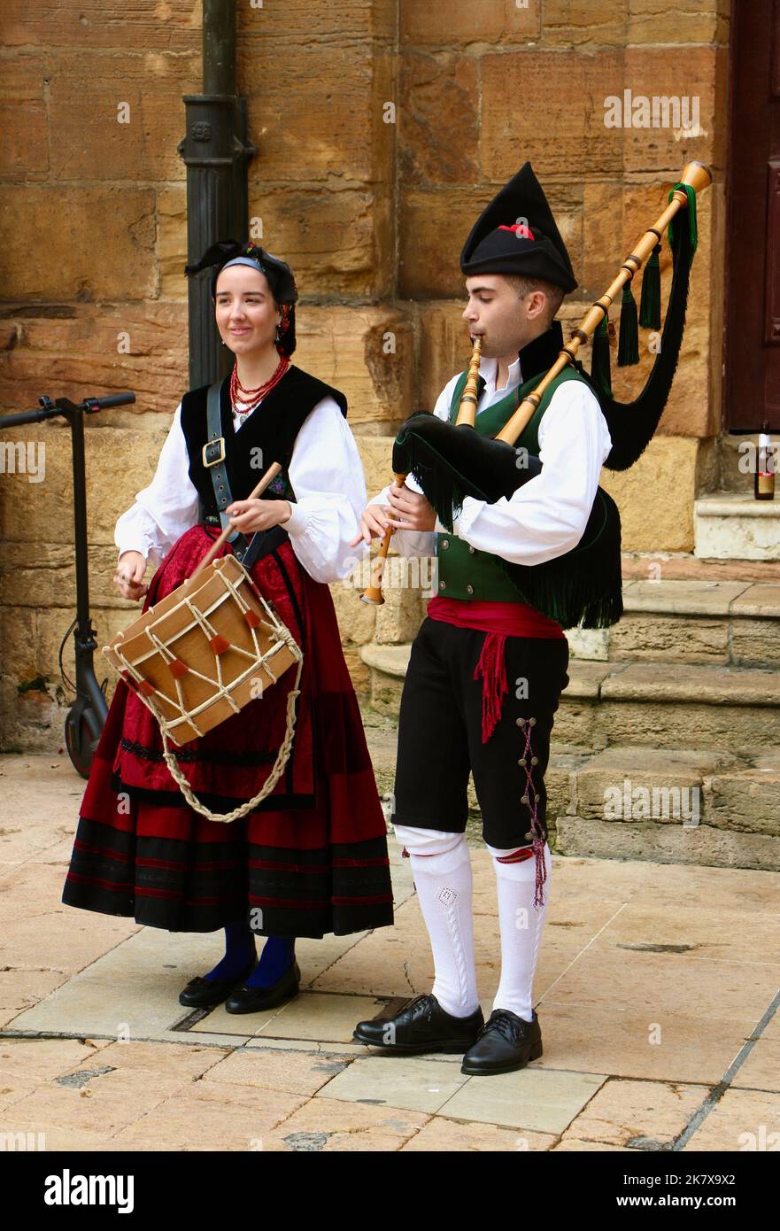 Two young musicians playing traditional music with a drum and bagpipes  in traditional clothes during the Disarmament parties Oviedo Asturias Spain Stock Photo