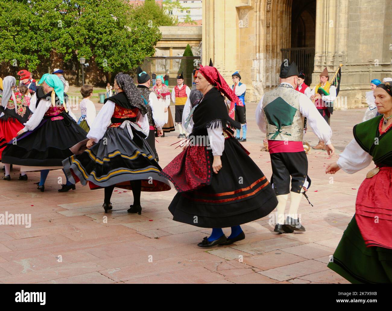 A folk dance group in traditional costumes dancing to bagpipe music in