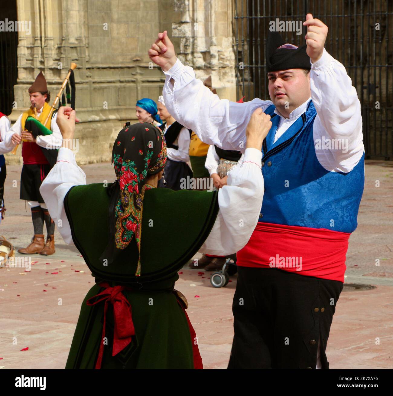 A folk dance group in traditional costumes dancing to bagpipe music in