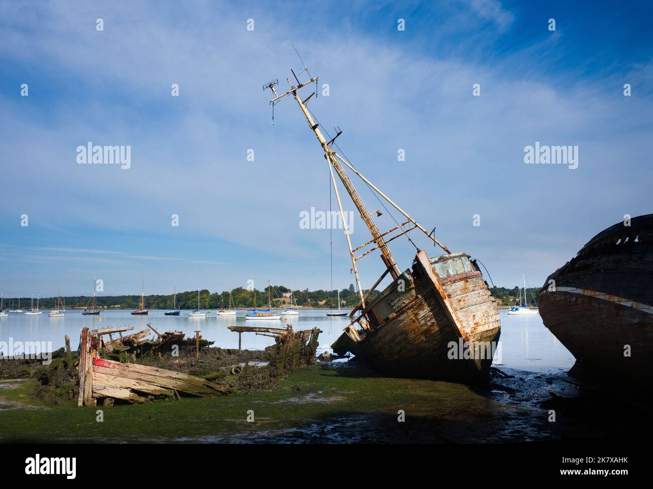 River Orwell moored boats with abandoned and wrecked wooden sailing boats on the foreshore in front Stock Photo