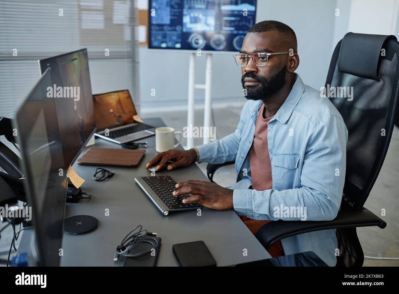 Portrait of black game developer working on level design and using computer in office Stock
