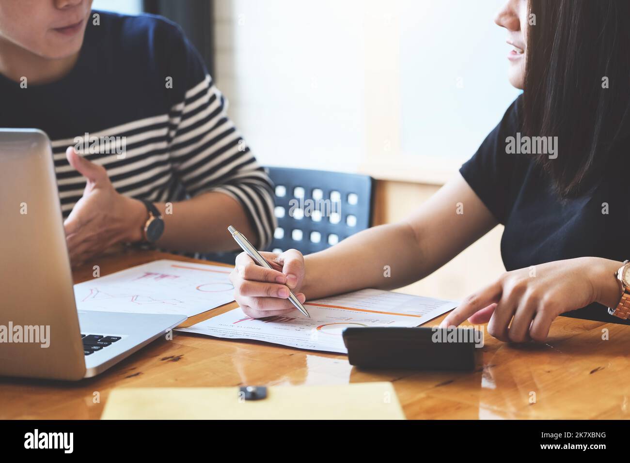 focus hand holding pen point to chart with discussion and exchange of