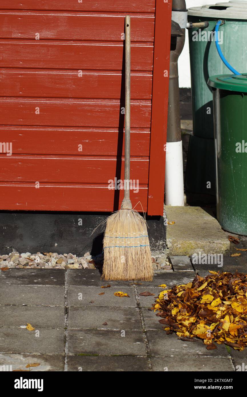 Handmade broom on wooden wall after sweeping autumn leaves Stock Photo