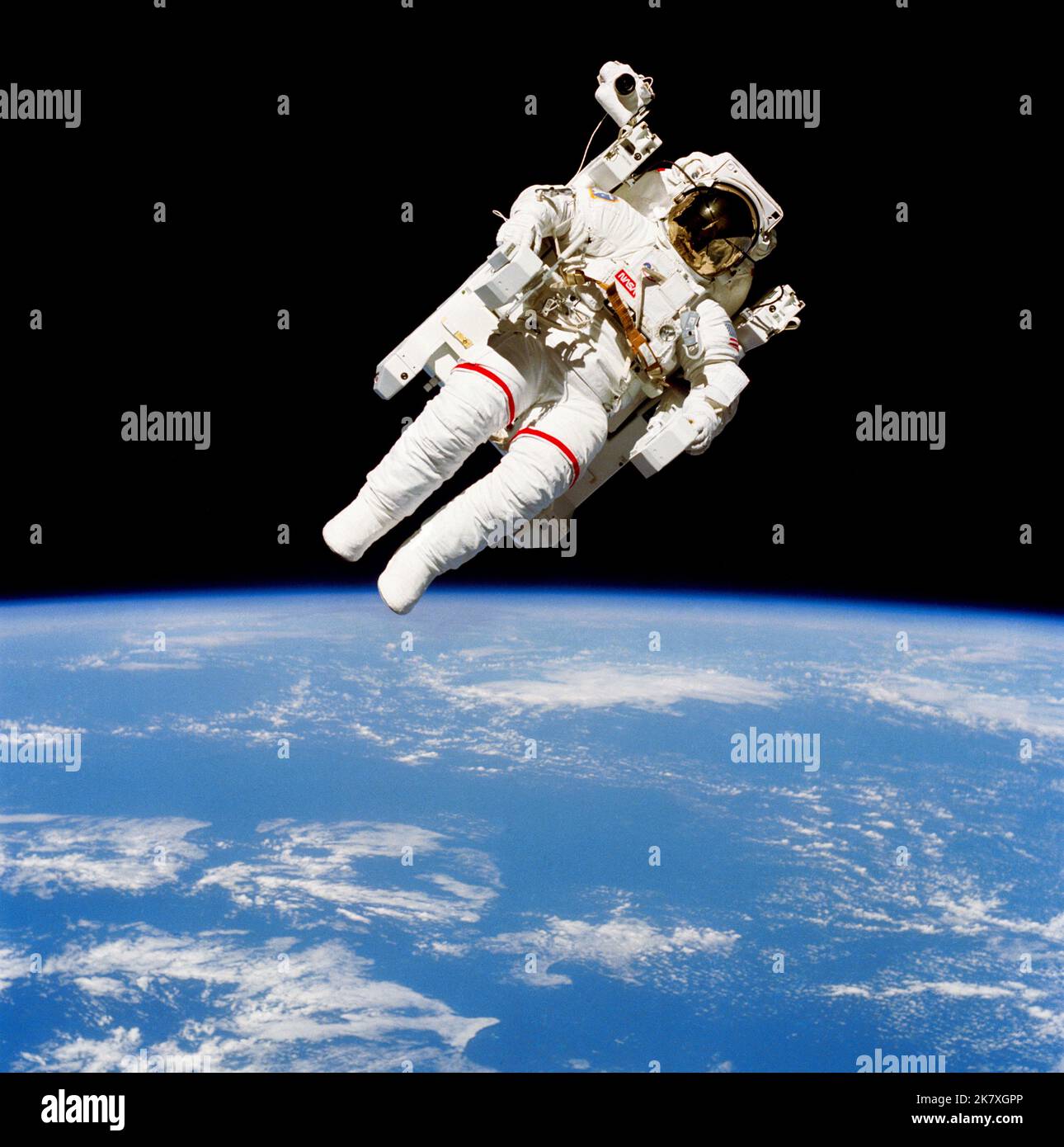 Astronaut Bruce McCandless II, STS 41-B mission specialist, participates in a historical spacewalk. He is pictured a few meters away from the cabin of the Earth-orbiting Space Shuttle Challenger. This spacewalk represented the first use of a nitrogen-propelled, hand-controlled device called the Manned Maneuvering Unit (MMU), which allows for much greater mobility than that afforded previous space walkers who had to use restrictive tethers. Bruce McCandless II demonstrates the Manned Maneuvering Unit (MMU), floating in space above a clouded Earth. Stock Photo