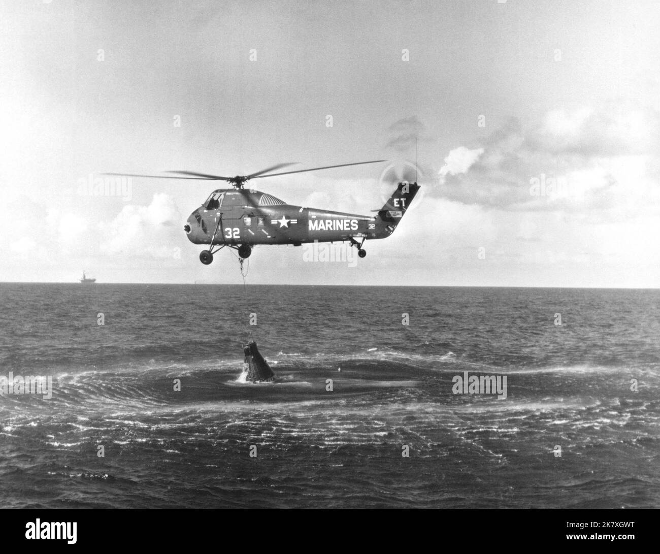 HUS-1 helicopter attempting to recover the Liberty Bell 7 spacecraft. The recovery ship USS Randolph is visible in the distance. Stock Photo