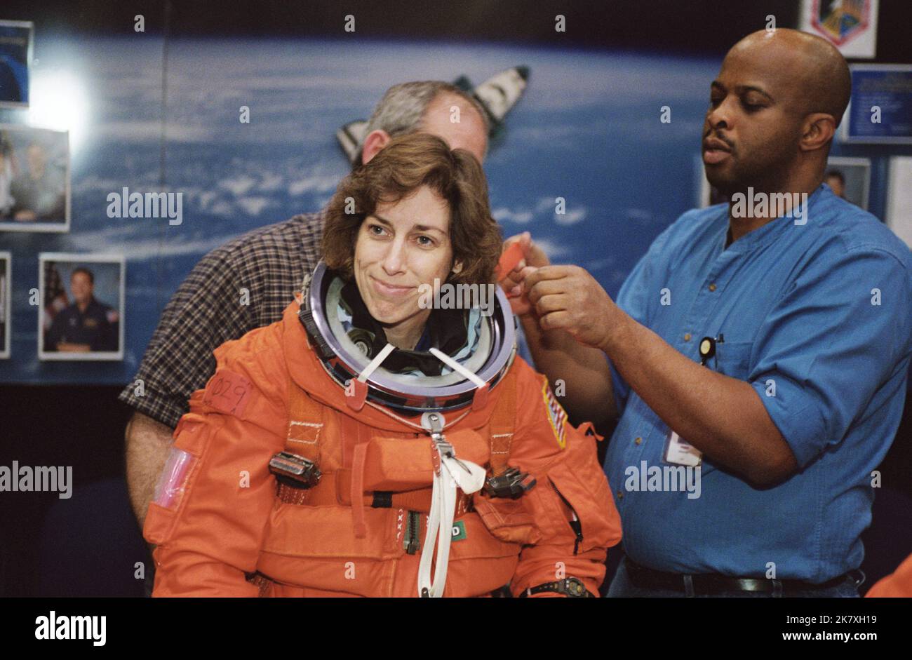 Astronaut Ellen Ochoa, STS-110 flight engineer, dons a training version of the full-pressure launch and entry suit prior to a training session in one of the trainer/mockups (out of frame) in the Space Vehicle Mockup Facility at the Johnson Space Center (JSC). Suit technician Andre Denard assists Ochoa. STS-110 was the 13th shuttle mission to visit the International Space Station (ISS). Stock Photo