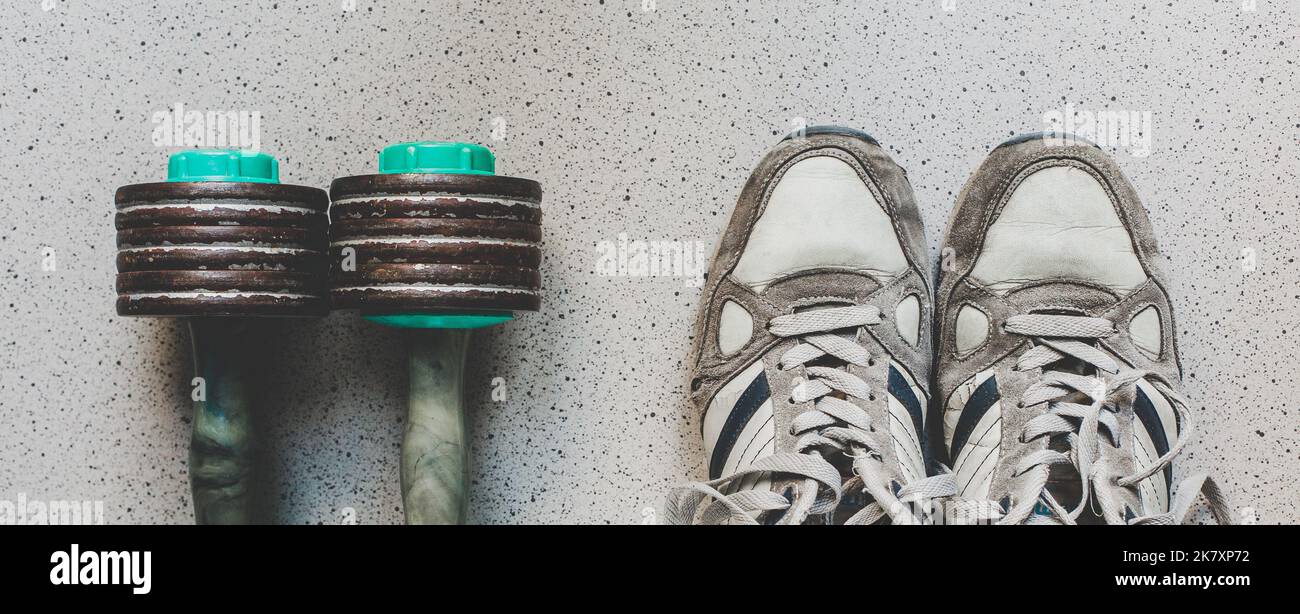 Vintage sport shoes and dumbbells on the floor, top view. Sport background Stock Photo