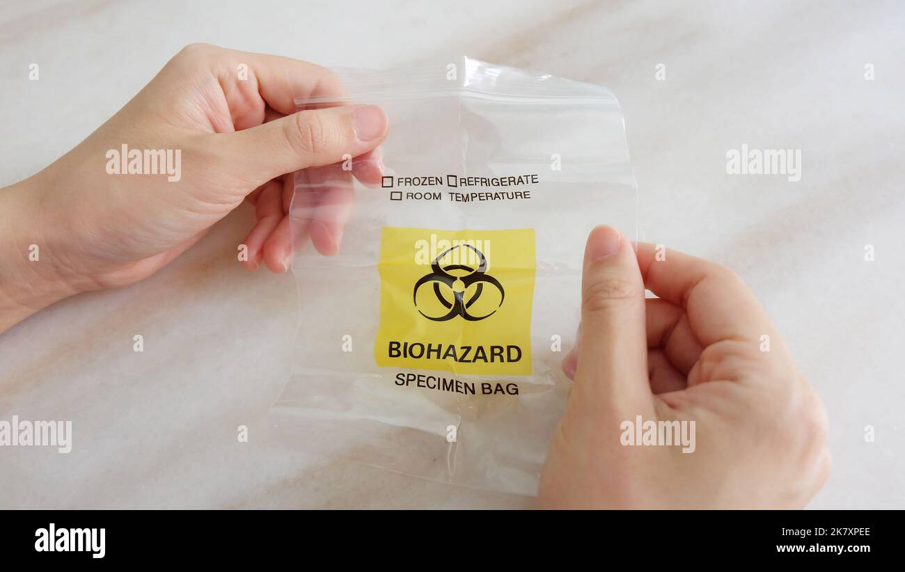 Hands holding a new and empty medical specimen waste bag with the