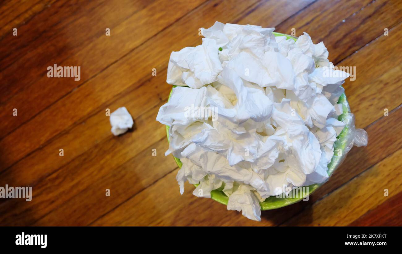 Top view of a small garbage bin full with used tissue paper, on wooden floor. Stock Photo