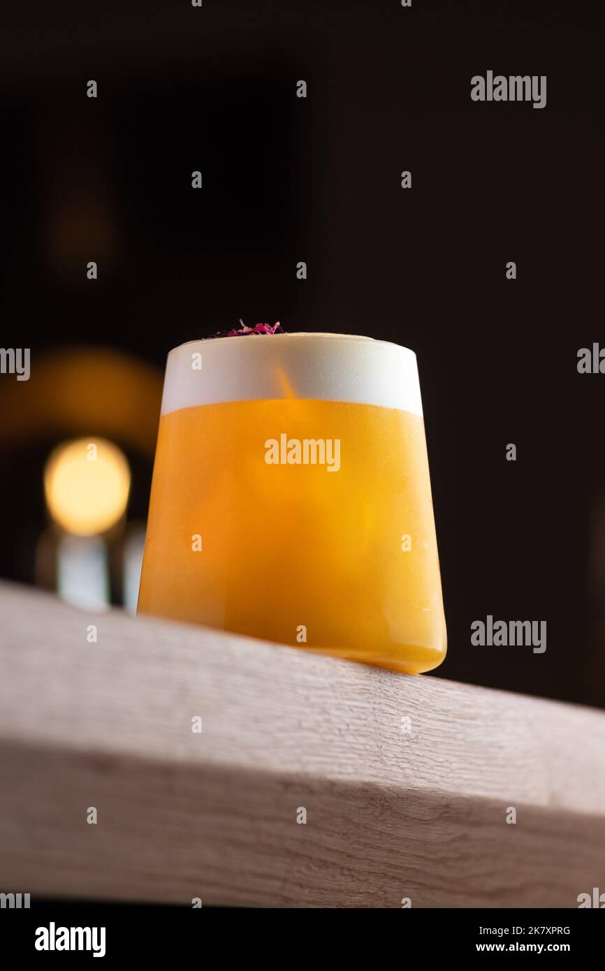 Orange colored cocktail with white foam on brown table, night mood image, copy space Stock Photo