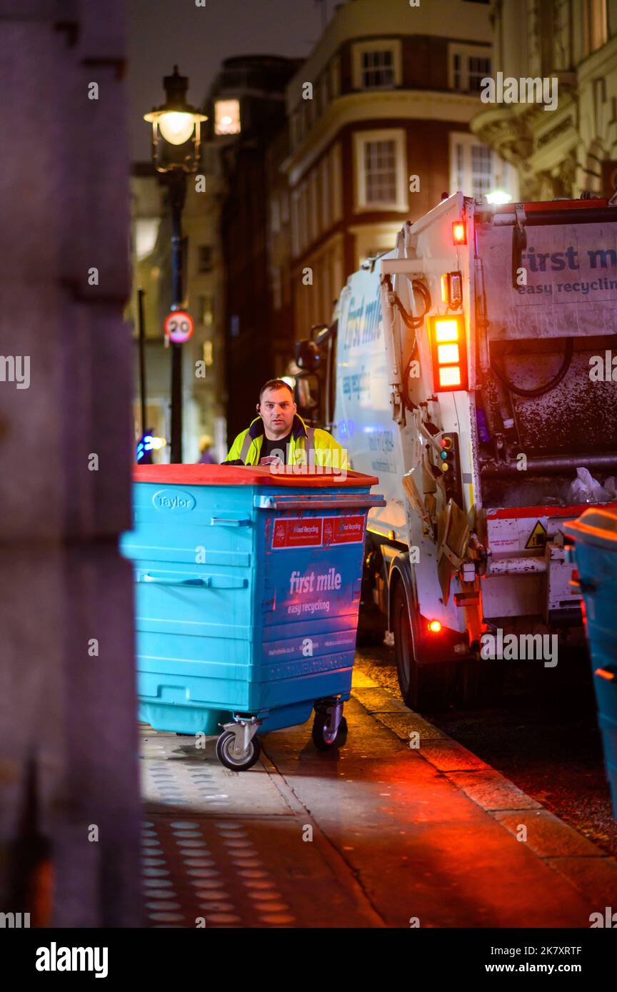 LONDON November 1, 2020 Bin man moves large wheelie bin on sidewalk