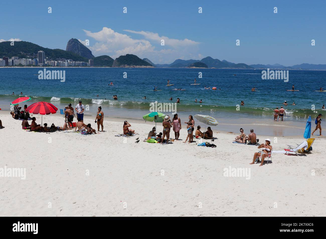 Copacabana beach, Rio de Janeiro, Brazil. People sunbathing near sea shore, colorful umbrellas. Crowd enjoy summer day swimming. Tropical travel place Stock Photo