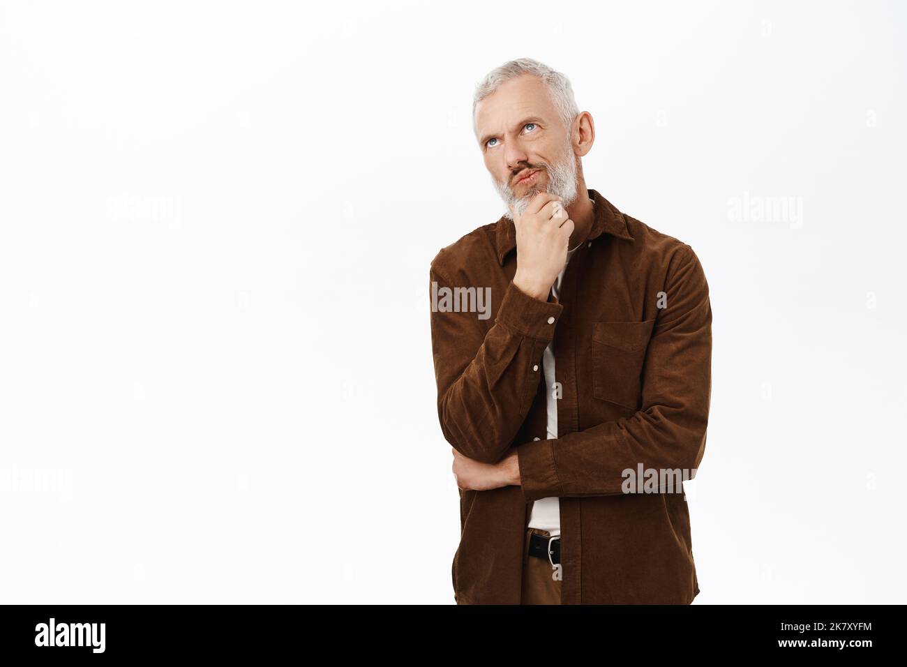 Thoughtful mature man, senior guy touching beard and thinking ...