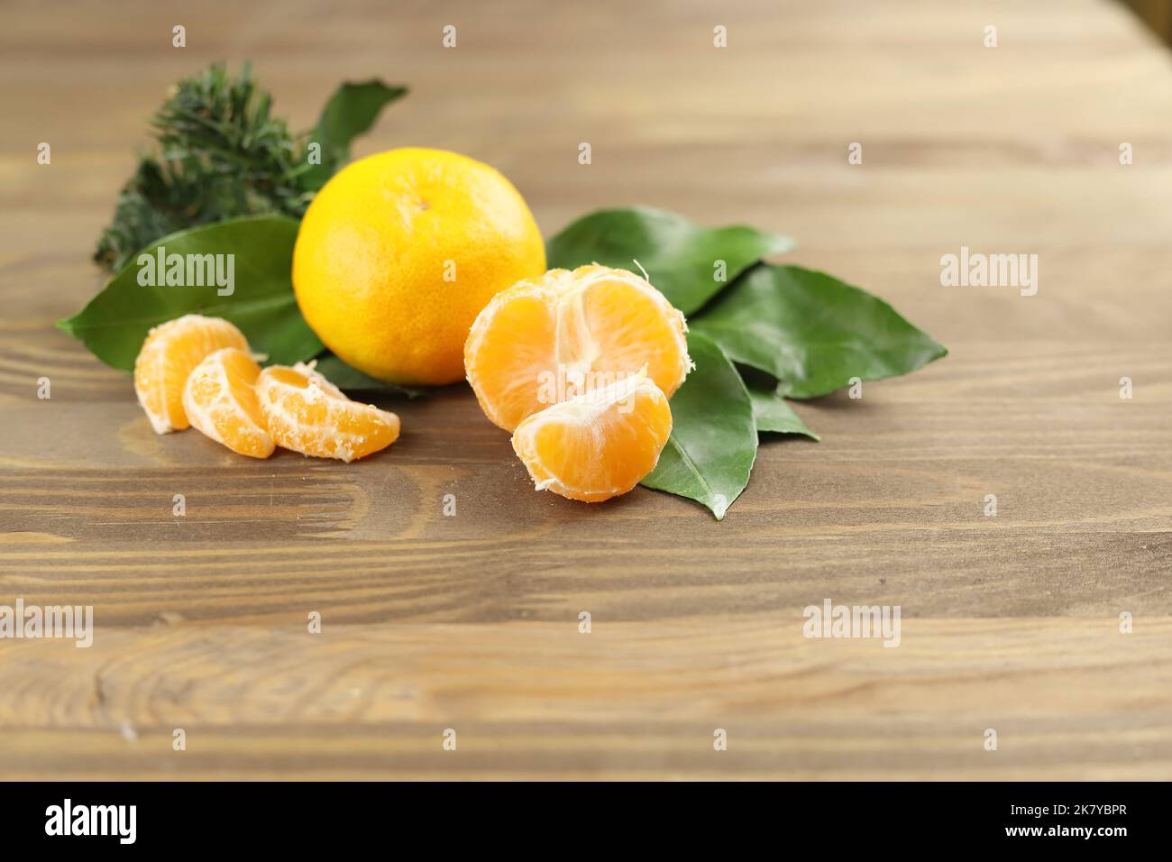 Mandarin or tangerine fruits whole and sliced, green leaves , fir tree on wooden background Stock Photo