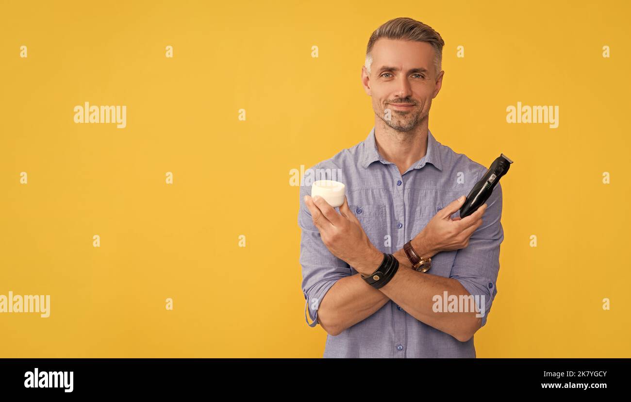 after shave. man holding electric shaver and cream. grizzled guy