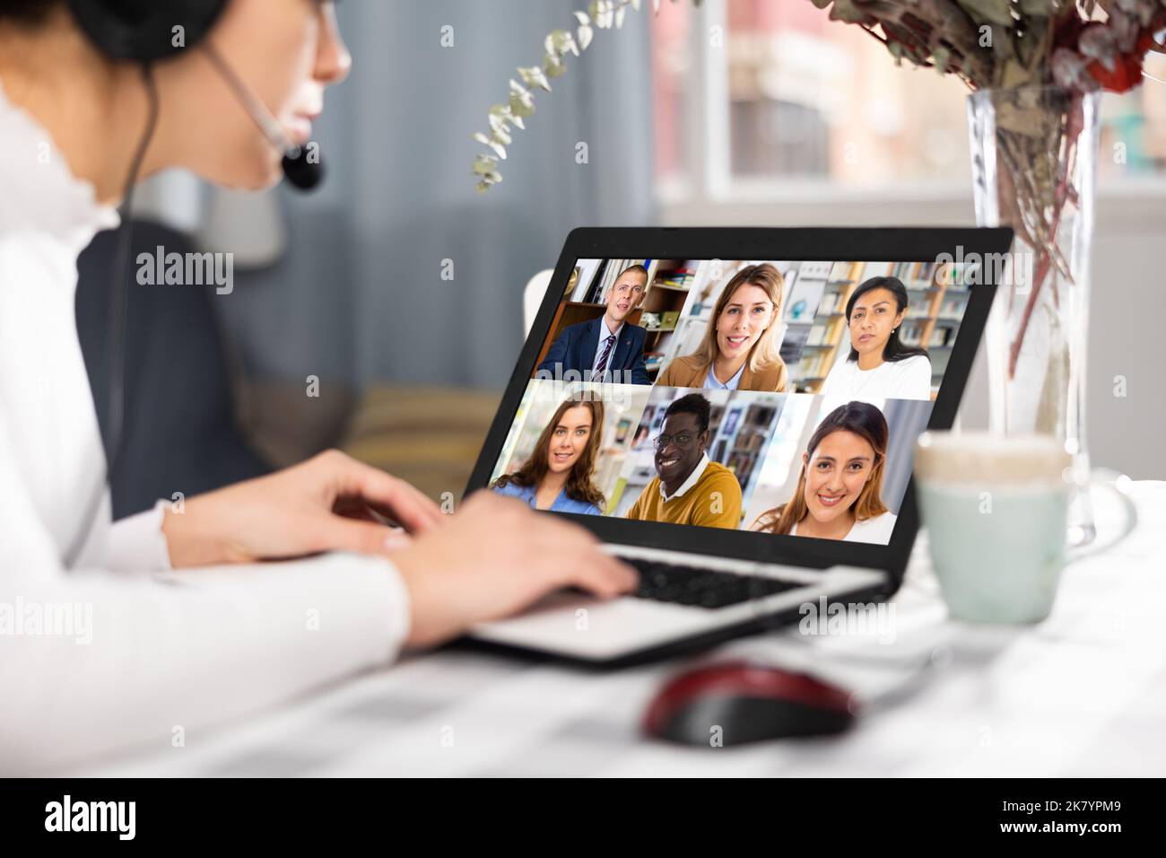 Young having conversation with her colleagues during video call Stock Photo