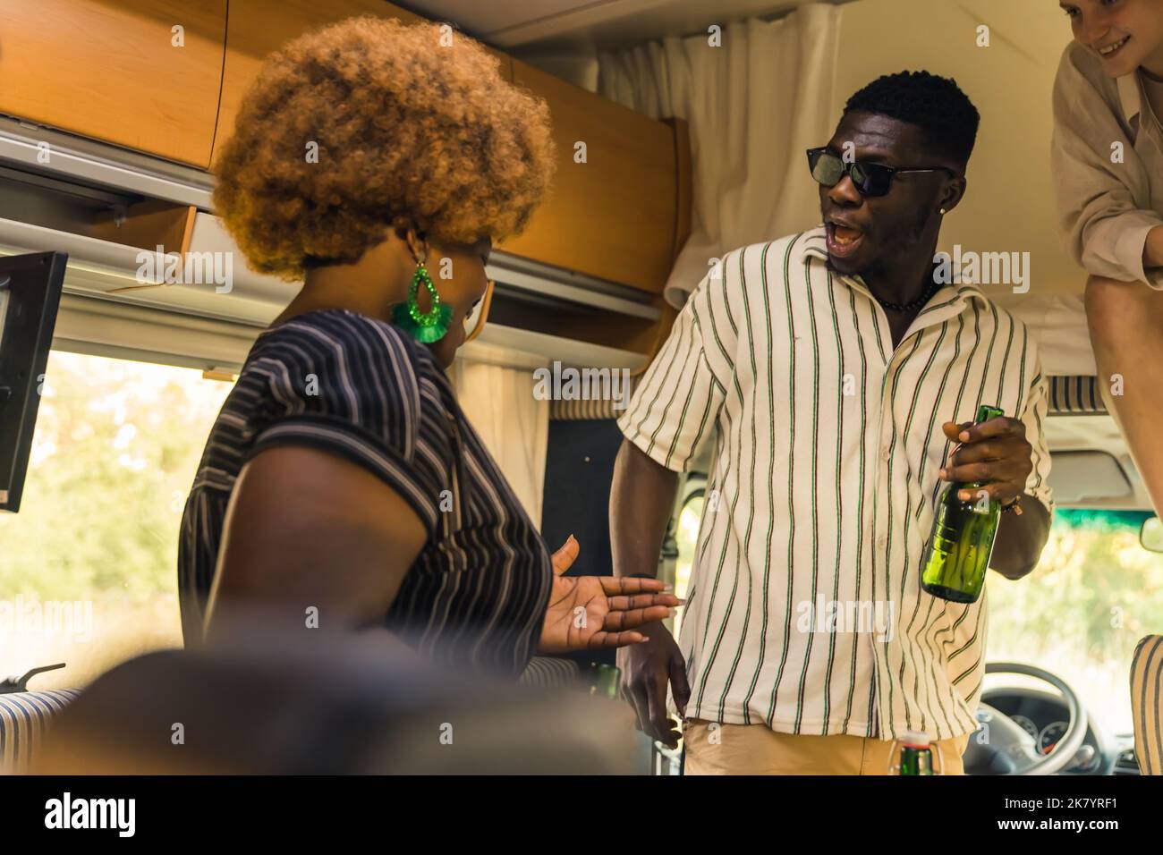 Adorable platonic best friends - Black woman and Black man - joking around and drinking beer during indoor camper party. High quality photo Stock Photo