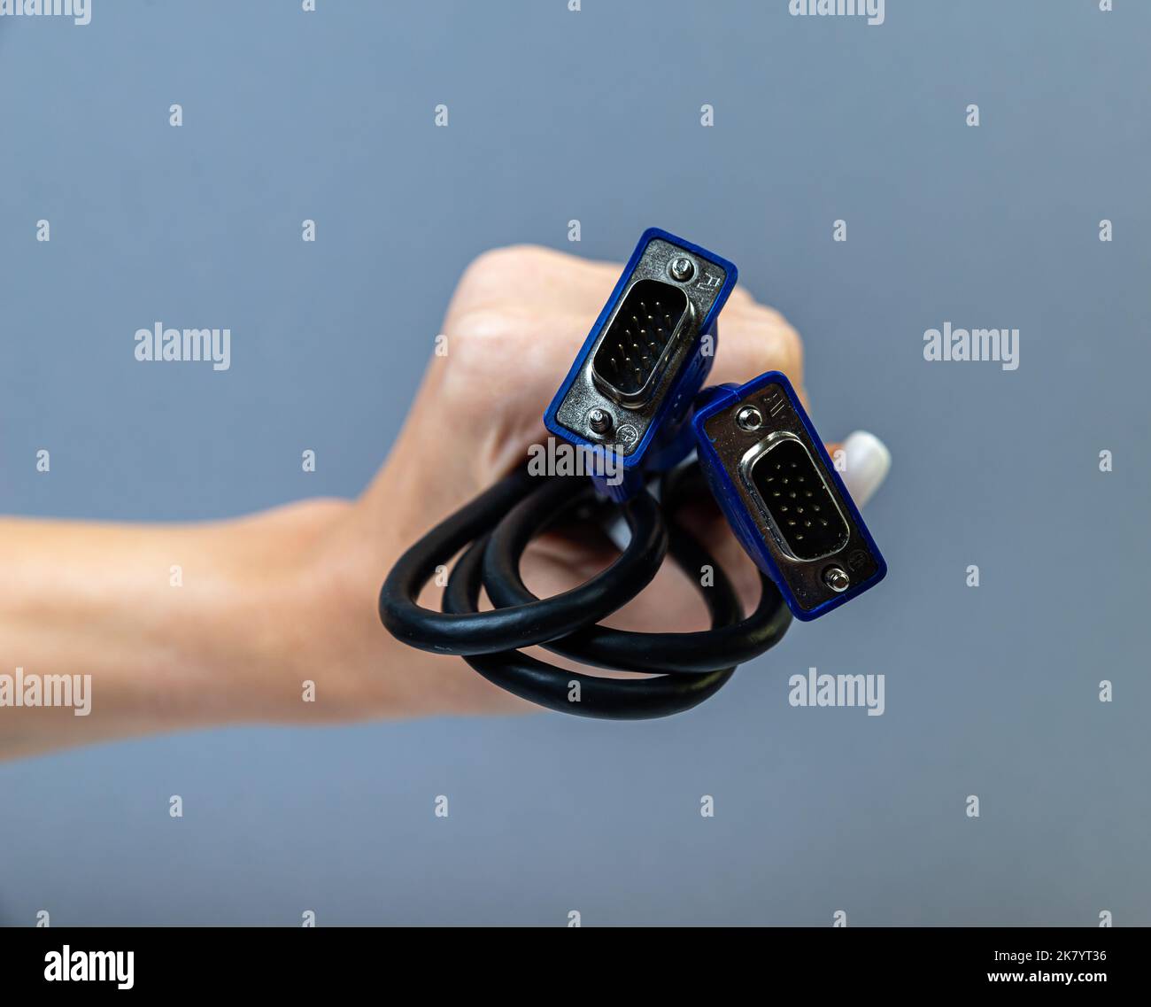Hand holding black VGA cable. Man's hand holds a VGA Connector. Closeup VGA cable.Selective focus and shallow Depth of field. Stock Photo