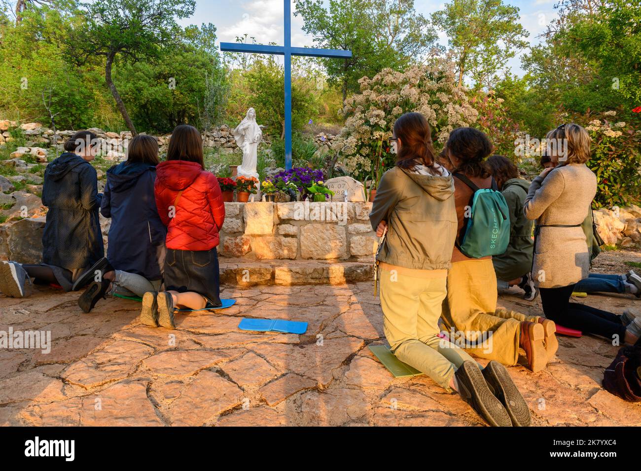 Young people kneeling and praying at the Blue Cross in Medjugorje, Bosnia and Herzegovina. Stock Photo