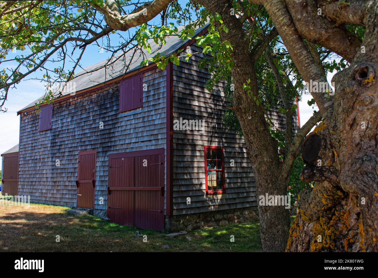 Wood shingle shed with red windows and doors on a sunny day at Cogswell