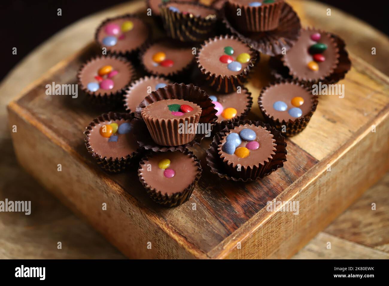 Selective focus. Macro. Small chocolate candies on a wooden board. Stock Photo