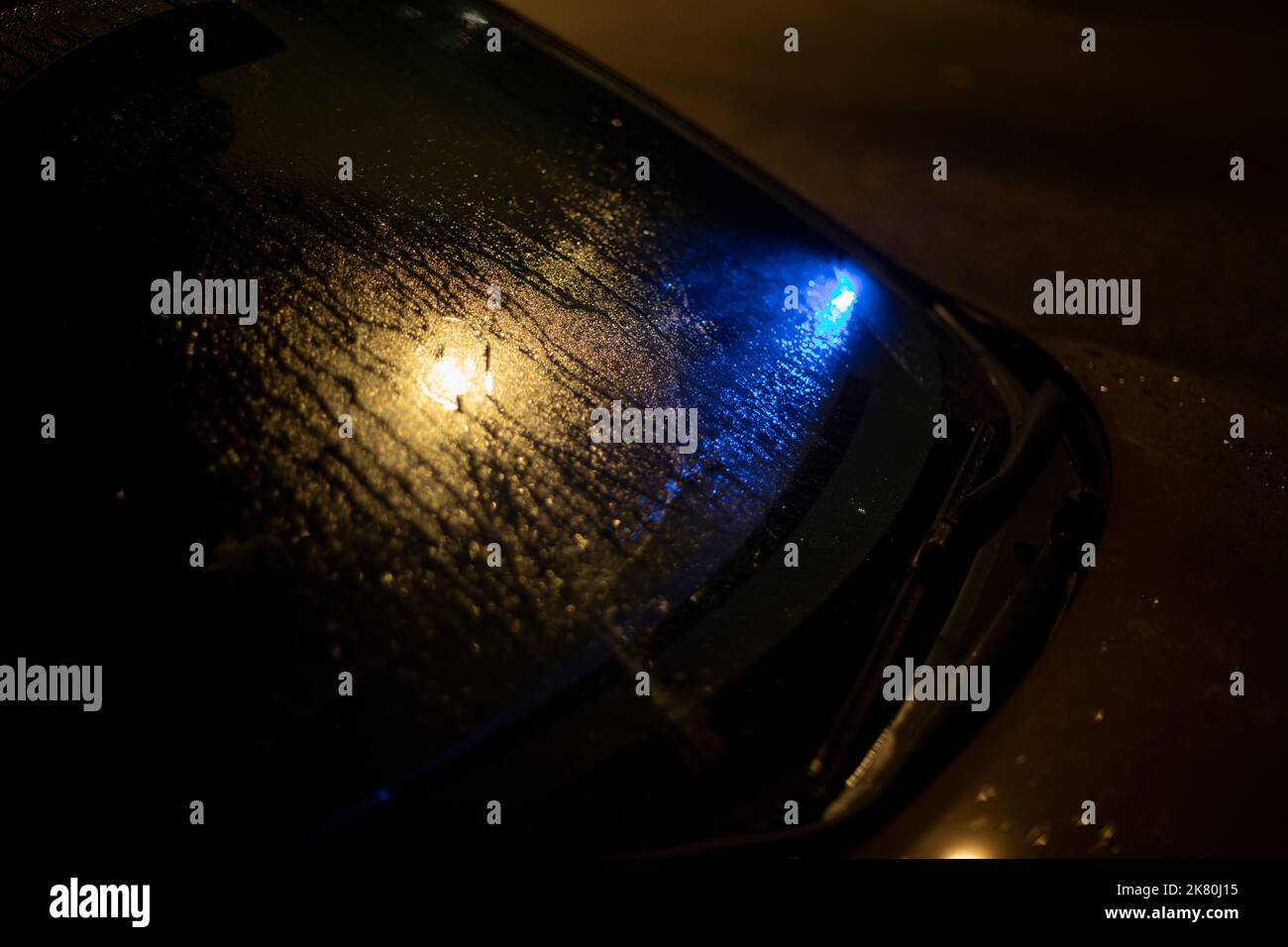 Blue signal under car glass. Signal light under wet window. Details of